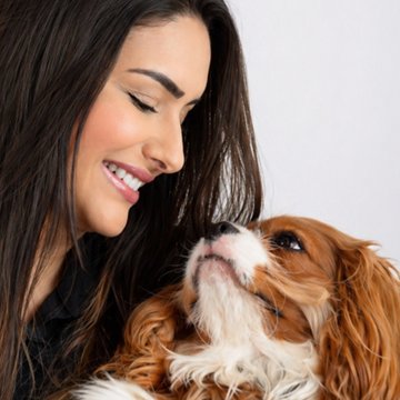 Dra. Fernanda Mirante sorrindo com um cavalier king charles no colo